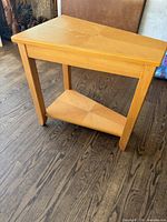 Full view of light oak side table showing top, legs, and lower shelf