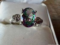 Front view of sterling silver ring showing oval mystic topaz and side motifs