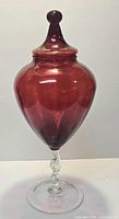 Full view of red cranberry glass covered urn showing lid, body, clear twisted stem and foot