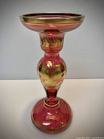 Full view of red glass candlestick showing gilt floral decoration and overall condition