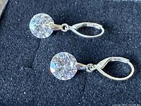 Pair of silver-tone cubic zirconia leverback earrings on display