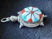 Overhead view of silver turtle pendant showing multicolour inlay detail