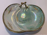 Top view of iridescent porcelain trinket dish showing branch-shaped handle, gold rim and dot accents