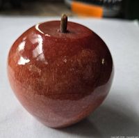 Front view of polished red stone apple with wood stem
