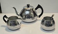 Teapot, creamer, sugar bowl with spoon showing overall design and condition