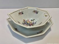 Stacked view of both porcelain bowls showing floral pattern, octagonal shape, handle and gold trim
