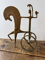 Full view of brass chariot sculpture standing on wood surface