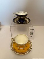 Two Aynsley cup and saucer sets, blue and yellow versions