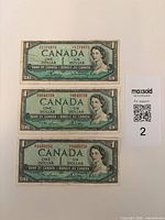 Fronts of three Canadian $1 notes with serial numbers visible