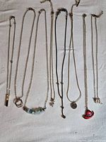 All eight necklaces laid flat in one frame to show quantity and pendant variety