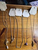 Five gold-tone necklaces on display cards