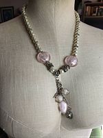 Full view of faux pearl necklace on bust showing pink glass beads and tassel drop