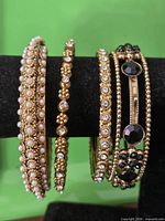 Four gold-tone bangles on display stand