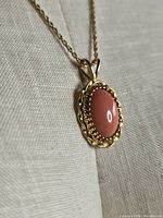 Close-up of pendant showing cabochon stone and decorative gold-tone setting