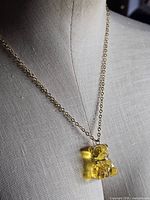 Necklace displayed on bust highlighting chain and yellow bear pendant