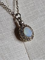 Close-up of pendant showing opalescent cabochon and clear rhinestones