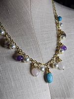 Full view of necklace on bust showing arrangement of dangling stones and faux pearls