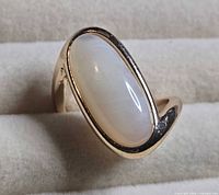 Front view of gold tone ring showing opal-colored cabochon and bezel setting