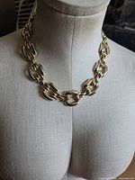 Front view of gold-tone flat link collar necklace displayed on form