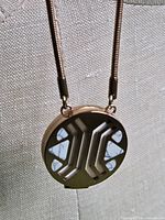 Close-up of pendant front showing geometric cut-outs and stone inlay