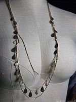 Necklace draped on dress form showing three tiers, teardrop charms, bar links and overall length
