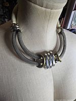 Necklace on bust showing front design with mesh tubes and stacked rings