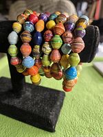 Bracelet on display stand showing multilayer coils of colorful paper beads