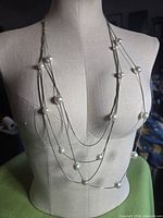 Necklace displayed on bust, showing layered strands and pearl spacing