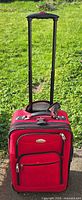 Front view of red Ricardo carry-on suitcase with telescopic handle extended
