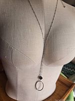 Necklace displayed on dress form showing full drop with black disc and oval pendant