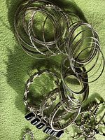 Pile of silver-tone bangles and three distinct link bracelets with black and green stone accents