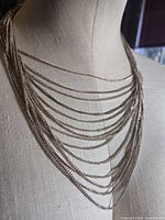 Front view showing layered silver-tone chains on bust