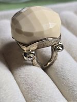 Close view of ring showing silver-tone setting, scroll details and ivory faceted dome stone