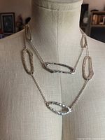 Full view of long necklace draped on mannequin showing link pattern and overall length