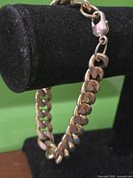 Close-up of entire gold-tone curb link bracelet on display stand