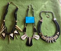 All three statement necklaces laid out on green surface