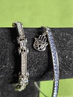 Close-up of both bracelets showing stone settings and hamsa charm