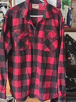 Front view of Wrangler red and black plaid flannel shirt hanging