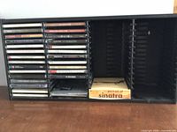 Full view of black plastic CD rack with CDs loaded on left side and empty slots on right
