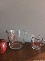 4-cup and 1-cup glass measuring cups side by side with an apple for scale