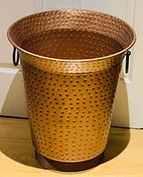 Front view of hammered copper container showing shape, texture, handle