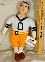 Front view of Curly Howard plush showing entire figure with ruler for scale and hang tag
