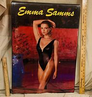 Front view of framed signed Emma Samms poster with rulers indicating size
