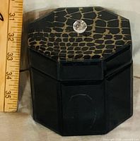 Closed box beside ruler showing size, lid pattern and knob handle
