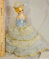 Front view of porcelain doll with ruler showing height