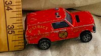 Left side view of red Matchbox Range Rover with ruler showing length