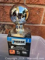 Front view of chrome Reese Towpower 2" hitch ball on packaging