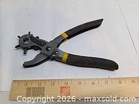Full view of rotary leather punch pliers beside ruler showing size