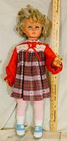 Front view of 31-inch vintage doll in plaid dress, tights and shoes next to ruler