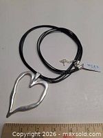 Full view of necklace showing black cords, heart pendant and attached MERX tag